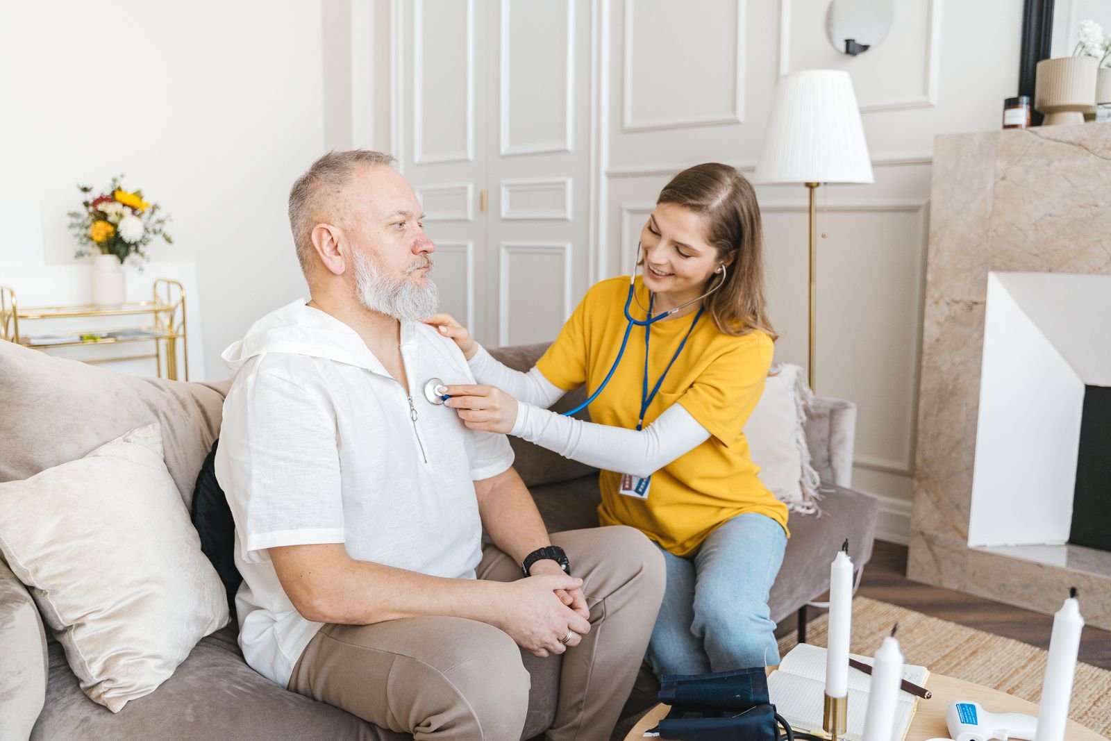 A home healthcare nurse smiling with an older adult in a sunlit living room