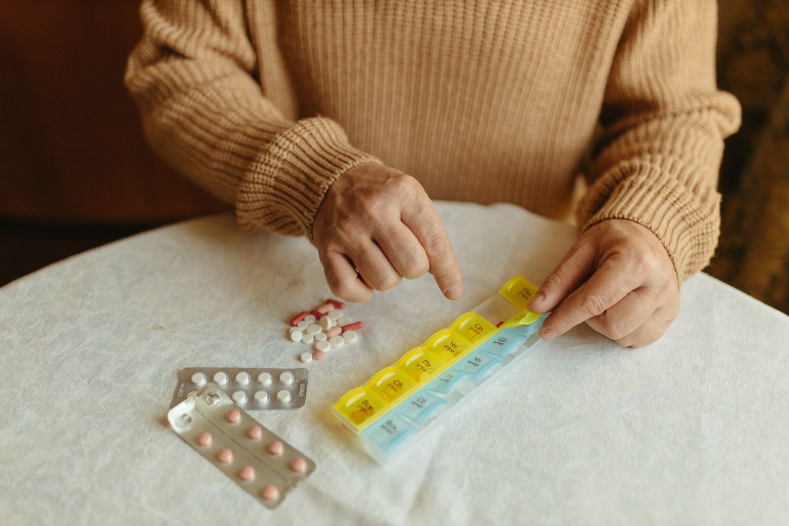 A person organizing medication into a weekly pill organizer to support daily reminders